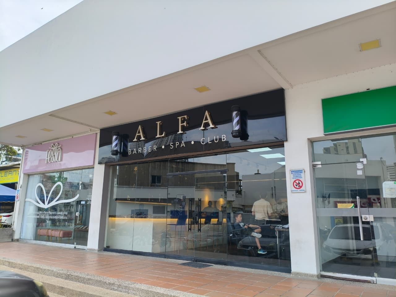 Fachada de ALFA Barber Spa Club en la Calle 84 de Barranquilla, con el letrero negro y dorado sobre el ventanal