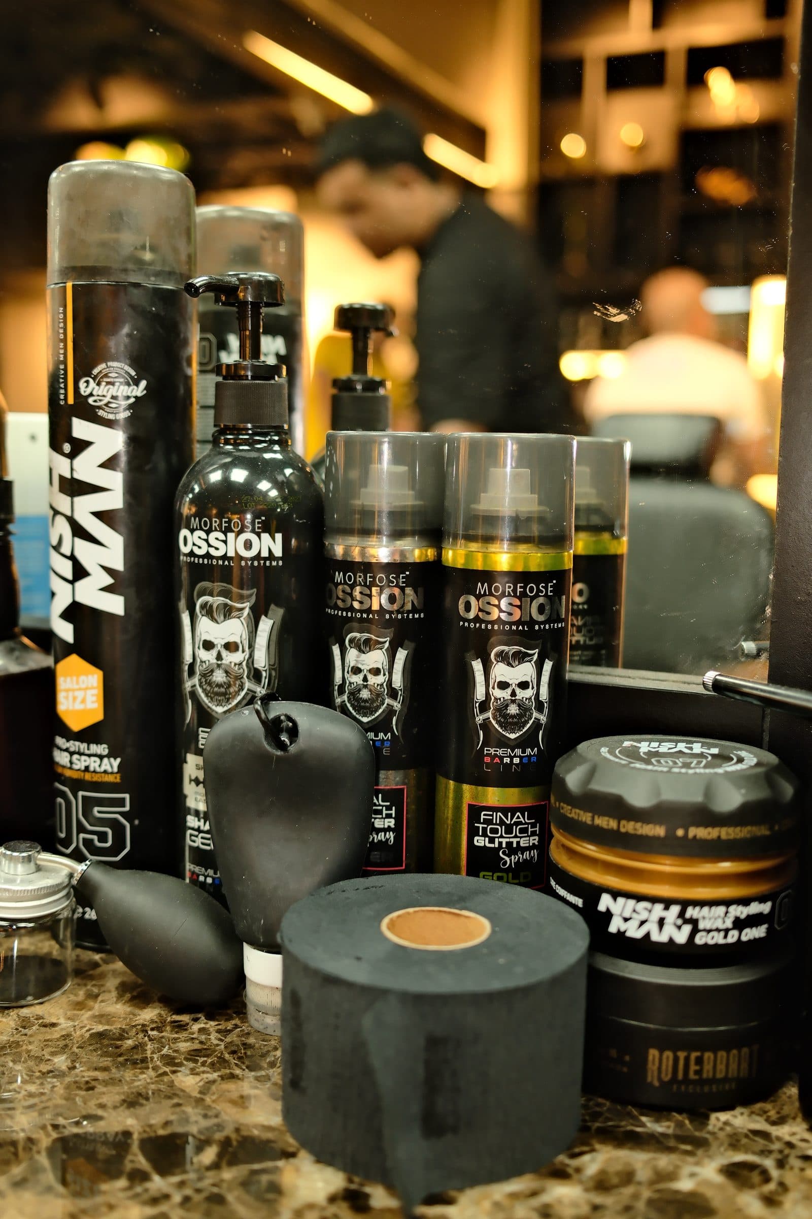Ceras, sprays y productos de peinado sobre el mueble de mármol de la barbería