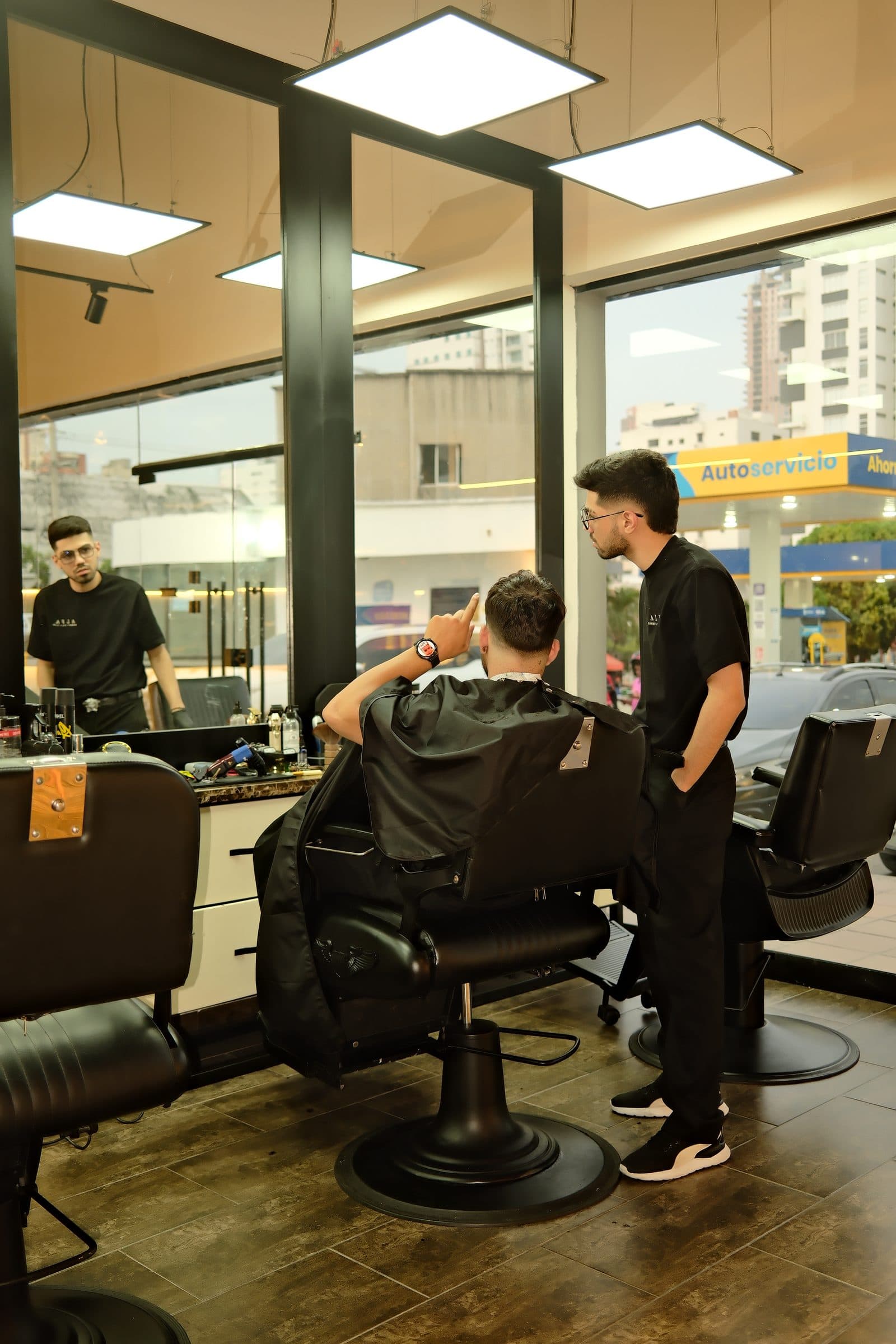Barbero atendiendo a un cliente junto al ventanal de ALFA Barber Spa Club